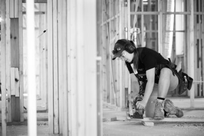 A woman is using a circular saw on a construction site