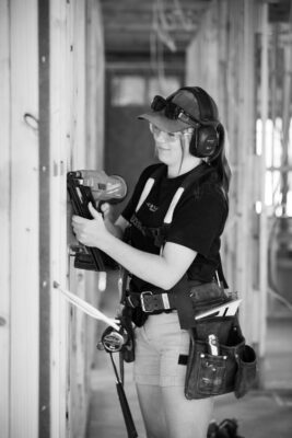 A woman is using a nail gun on a construction site